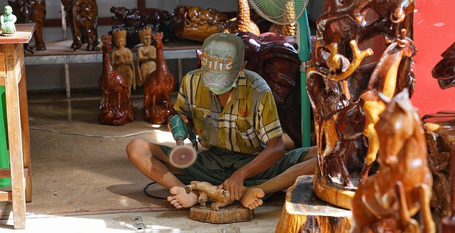 A male carver using a wood sanding tool