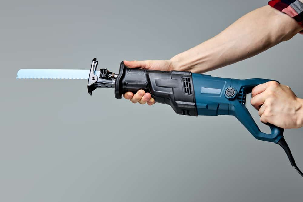 Reciprocating saw used in construction and demolition work, in male hands