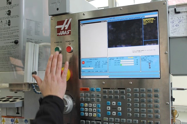 a hand about to press the power on button on a CNC machine