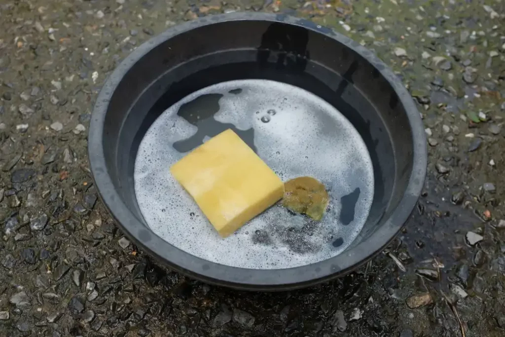 Scotch Brite in a plastic basin for washing dishes on cement floor