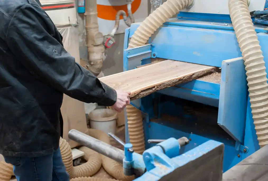 A thickness planner smoothing a piece of wood and thickening it.